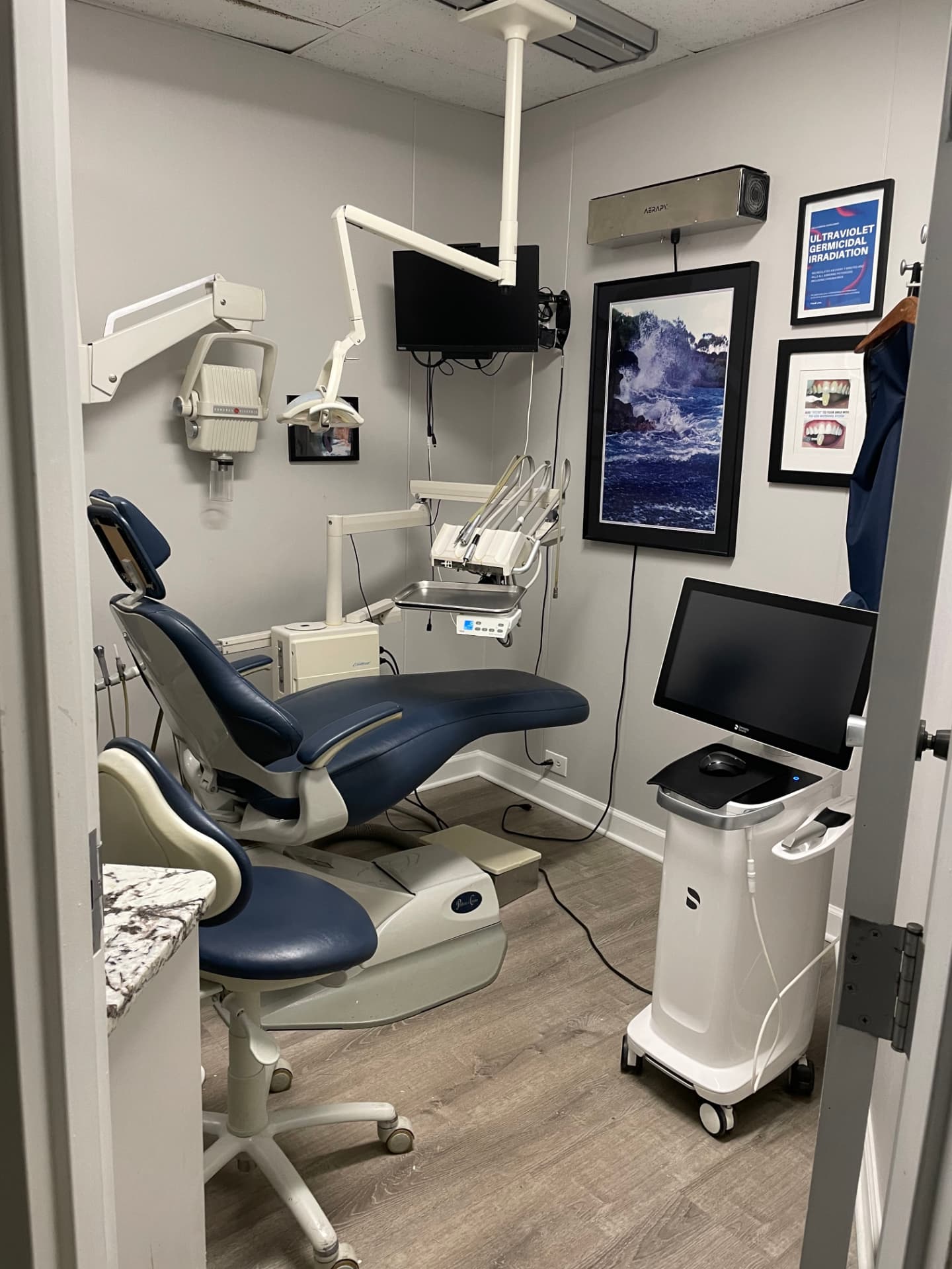 Treatment room with dental chair, chairside monitor, and CEREC same-day crown milling unit
